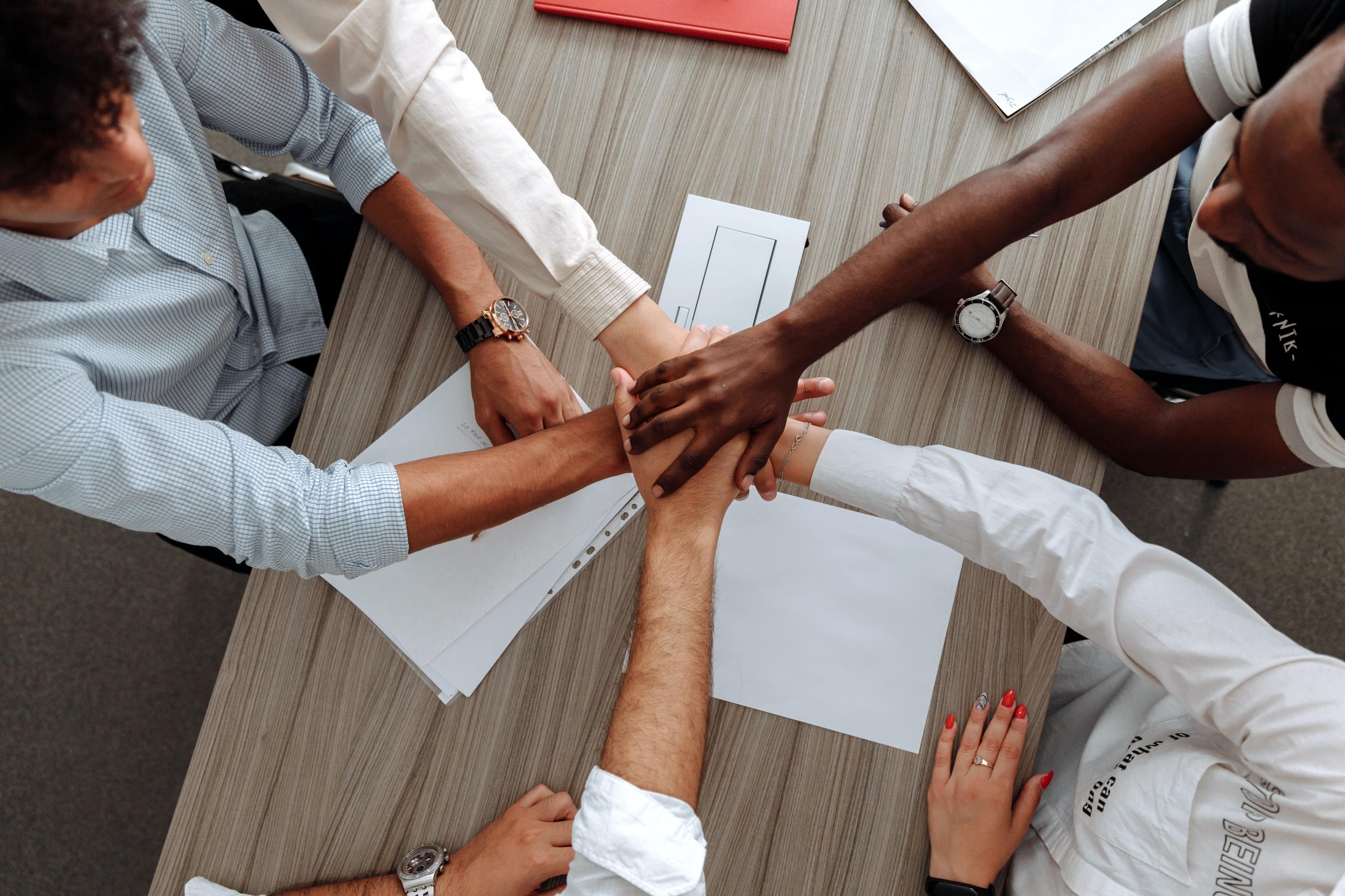 Homepage/three men and one woman joining hands at office meeting.jpg