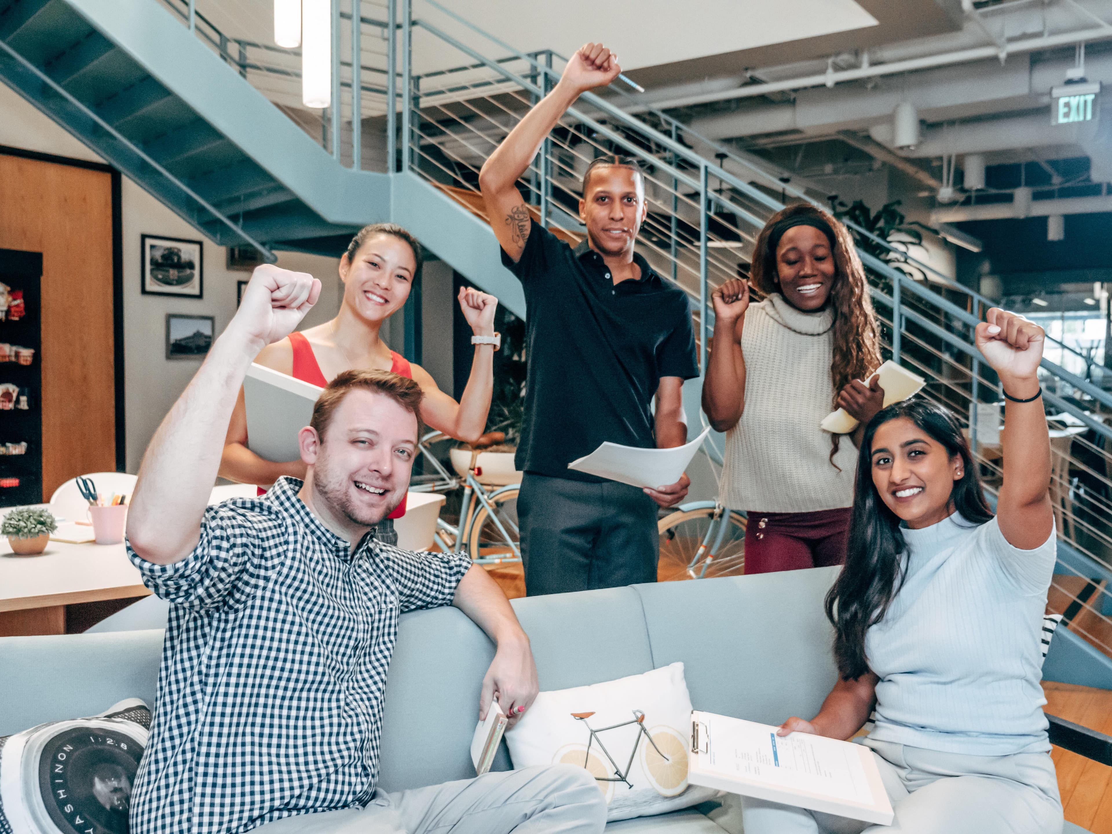Homepage/two men and three women raising hand on couch in office.jpg